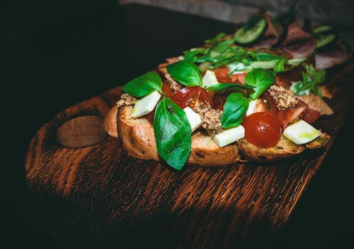 Tartine garnie de tapenade, tomates cerises et basilic sur une planche en bois, idéale pour un apéro maison.