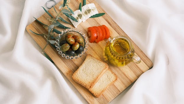 Plateau apéritif avec pains sans pétrissage, tapenade, olives, tomates et huile d'olive sur un fond blanc.